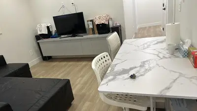 a living room with a white table and a tv at Metrotown area in Vancouver