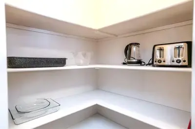 a small kitchen with white shelves and appliances at Luxe Escape Duo - 8 Beds - Sleeps 22 - 4 Car Garage in Edmonton