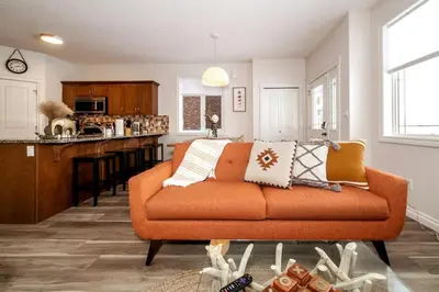 a living room with an orange couch and a kitchen at Luxe Escape Duo - 8 Beds - Sleeps 22 - 4 Car Garage in Edmonton