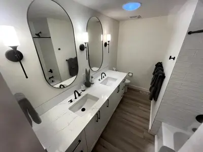 a white bathroom with two sinks and two mirrors at Camelia Home in Kelowna