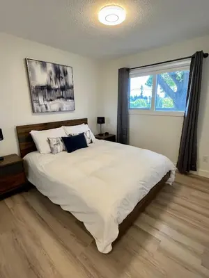 a bedroom with a large white bed and a window at Camelia Home in Kelowna