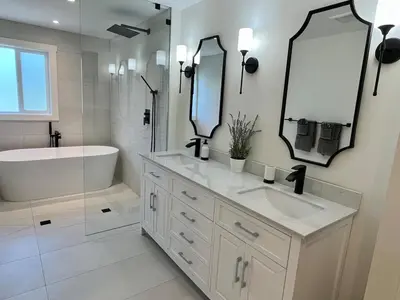 a white bathroom with a tub and a sink and mirror at Camelia Home in Kelowna