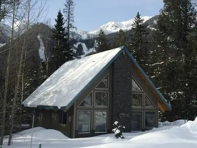 a building with a snow covered roof in the snow at True North Chalet by Fernie Central Reservations in Fernie