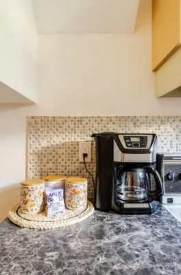 a kitchen counter with a coffee maker and three cups at Spacious & Cozy 1 Bedroom Suite in North Vancouver in North Vancouver