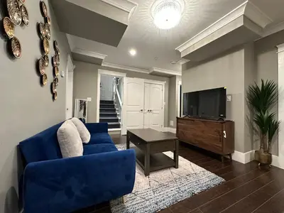 a living room with a blue couch and a tv at Bright New 2BR Suite Near YVR in Vancouver