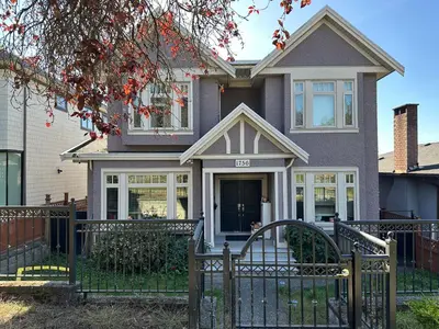 a house with a black fence and a gate at Bright New 2BR Suite Near YVR in Vancouver