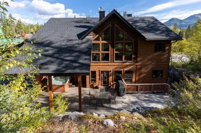 a woman standing on a deck in front of a house at Black Diamond Chalet by Fernie Central Reservations in Fernie