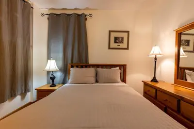 a bedroom with a bed with two lamps and a mirror at Black Diamond Chalet by Fernie Central Reservations in Fernie