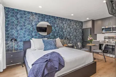 a bedroom with a large bed and a kitchen at Chick and Cozy Haven near Banff with Hot tub and Pool in Canmore