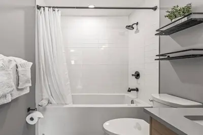 a white bathroom with a tub and a toilet at Chick and Cozy Haven near Banff with Hot tub and Pool in Canmore