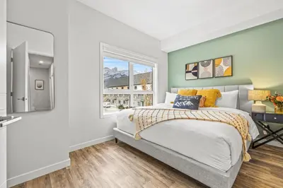 a bedroom with a bed and a window at Mountain Modern 2BR Townhome with Stunning View in Canmore