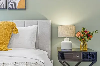 a bed with a table with a lamp and a vase with flowers at Mountain Modern 2BR Townhome with Stunning View in Canmore