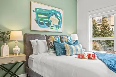 a bedroom with a white bed with blue pillows at Mountain Modern 2BR Townhome with Stunning View in Canmore