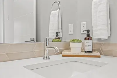 a bathroom sink with a bottle of soap and a mirror at Mountain Modern 2BR Townhome with Stunning View in Canmore