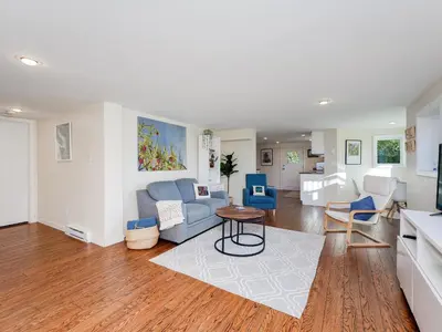 a living room with a couch and a table at Gallery Garden - stylish, art-filled 1-bedroom suite by Victoria Prime! in Victoria