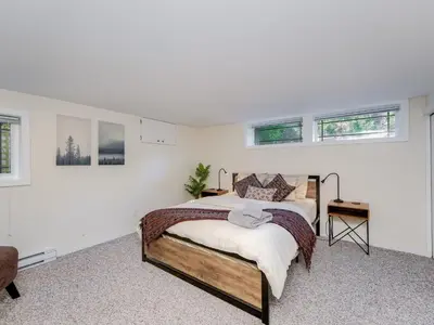 a bedroom with a bed in a room with windows at Gallery Garden - stylish, art-filled 1-bedroom suite by Victoria Prime! in Victoria
