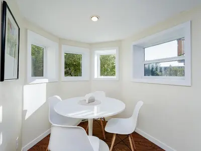 a white dining room with a white table and chairs at Gallery Garden - stylish, art-filled 1-bedroom suite by Victoria Prime! in Victoria