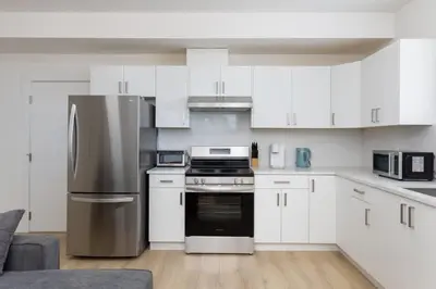 a kitchen with white cabinets and a stainless steel refrigerator at Tranquil 2-Bedroom Basement Suite Relaxing Stay in Chilliwack