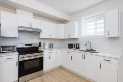 a white kitchen with white cabinets and a sink at Tranquil 2-Bedroom Basement Suite Relaxing Stay in Chilliwack