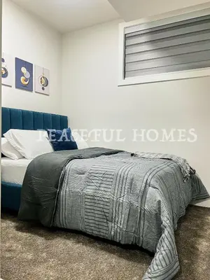 a bedroom with a bed and a blue couch at Peaceful Homes - Elegant 2 Bedroom Suite in Calgary
