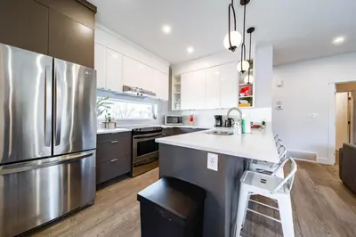 a kitchen with a stainless steel refrigerator and a stool at 9BDRM Chic Luxury Retreat-Hot Tub-BBQ-Sleeps 23! in Edmonton