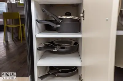 a cupboard with a pot and pans in it at Dual-Suite Getaway - Sleeps 12 - Whyte Ave - NFLX in Edmonton