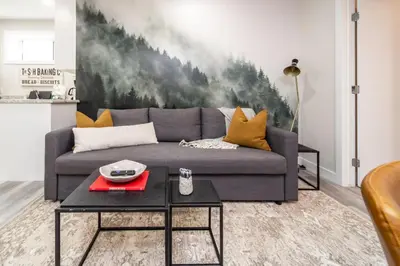 a living room with a gray couch and a table at Dual-Suite Getaway - Sleeps 12 - Whyte Ave - NFLX in Edmonton