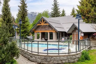 a house with a swimming pool in front of a house at Private Hot Tub | Free Parking | Pool | Sauna in Whistler