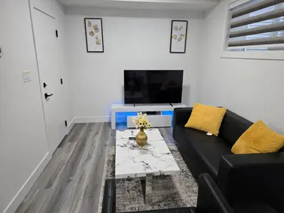 a living room with a black couch and a tv at L&D Luxury Suite in Nisku