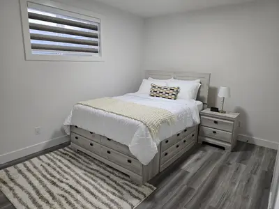 a white bedroom with a bed and a window at L&D Luxury Suite in Nisku