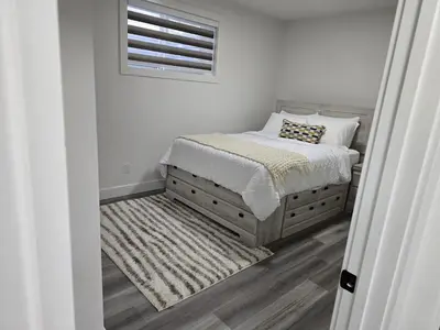 a white bedroom with a bed and a window at L&D Luxury Suite in Nisku