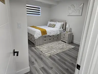 a white bedroom with a bed and a night stand at L&D Luxury Suite in Nisku