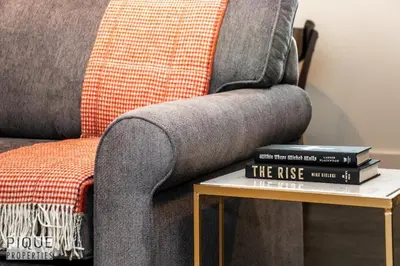 a pile of books on a table next to a couch at Bright Modern Suites-King Beds-NFLX-WiFi-LongStays in Edmonton