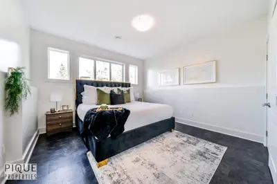 a bedroom with a bed with a black headboard and windows at Bright Modern Suites-King Beds-NFLX-WiFi-LongStays in Edmonton