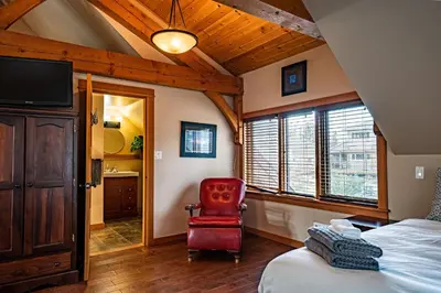 a bedroom with a bed and a red chair at Timberloft by Revelstoke Vacations in Revelstoke