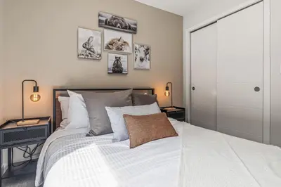 a bedroom with a white bed and some pictures on the wall at Rockies Escape for Groups with Hot tub and Pool in Canmore