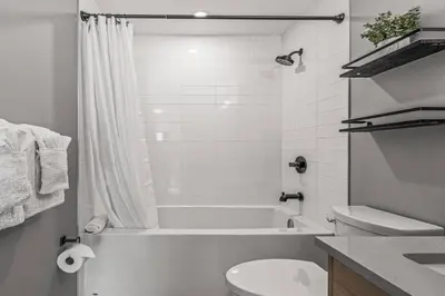a white bathroom with a tub and a toilet at Rockies Escape for Groups with Hot tub and Pool in Canmore