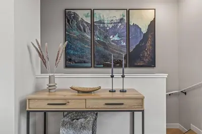 a table in a room with four paintings on the wall at New 3BR with Mountain Views Near DT Hot Tub and Pool in Canmore