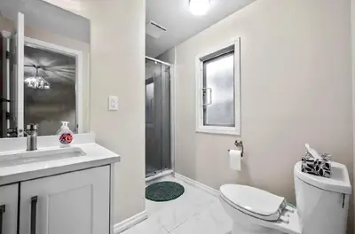 a white bathroom with a toilet and a sink at Bright Maple Suite in Richmond