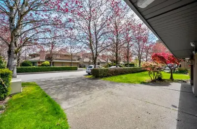 a driveway with a car parked in a yard with trees at Bright Maple Suite in Richmond