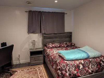 a bedroom with a bed and a lamp and a window at 2-Room Suite in South Edmonton in Edmonton