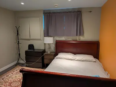a bedroom with a bed and a lamp and a window at 2-Room Suite in South Edmonton in Edmonton