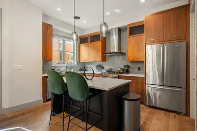 a kitchen with wooden cabinets and a stainless steel refrigerator at *Incredible Location* |Two King Beds| Free Parking in Calgary