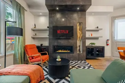 a living room with a fireplace and orange chairs at THE Getaway For BIG Groups-DT in Calgary