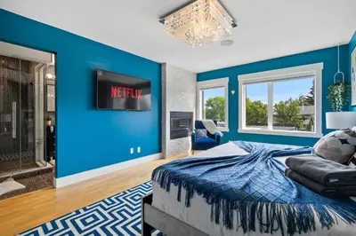 a bedroom with a blue accent wall and a bed at *Everything*| Hot Tub| Sauna| Pool table|Game Room in Calgary