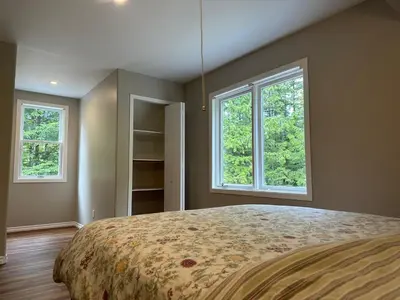a bedroom with a large bed with two windows at Charming 4-Bedroom Home in Bella Coola in Hagensborg