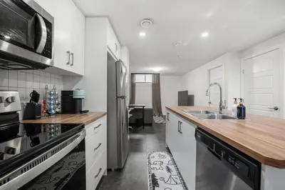 a kitchen with white cabinets and a stainless steel refrigerator at Modern Suburban Retreat in Ambleton Stylish Comfort Near Parks and Trails in Calgary