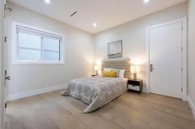 a white bedroom with a bed and a window at Excellent Place to Stay in Coquitlam