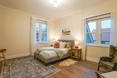 a bedroom with a bed and a chair and windows at Samson House in Revelstoke