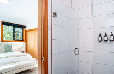 a white bathroom with a shower and a bed at Cartier Chalet in Revelstoke